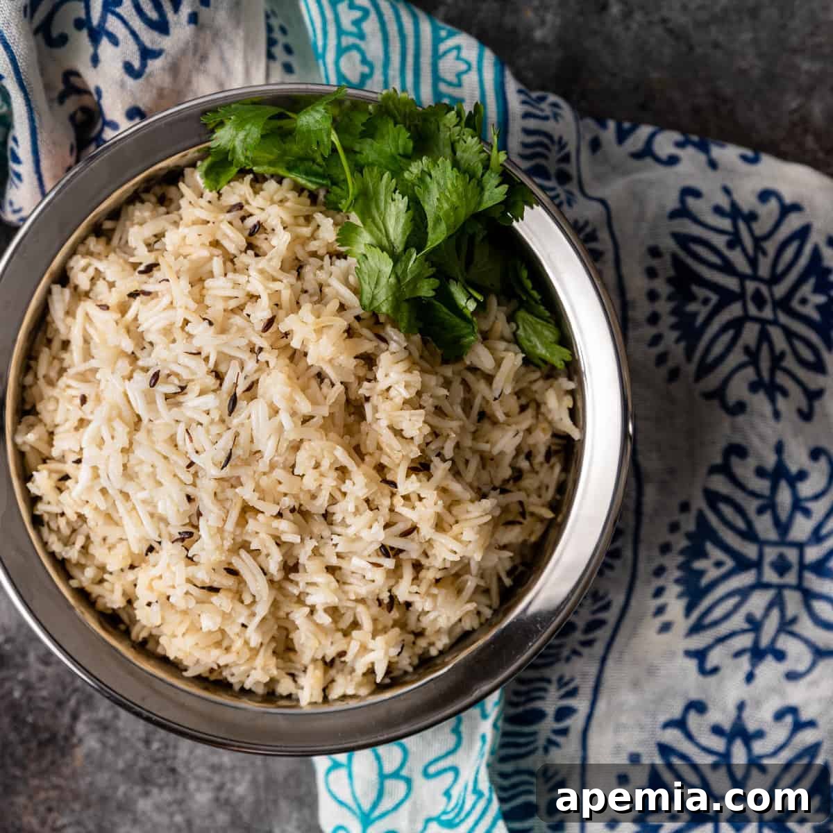 Aromatic Jeera Rice 2 overhead: bowl of jeera rice garnished with parsley