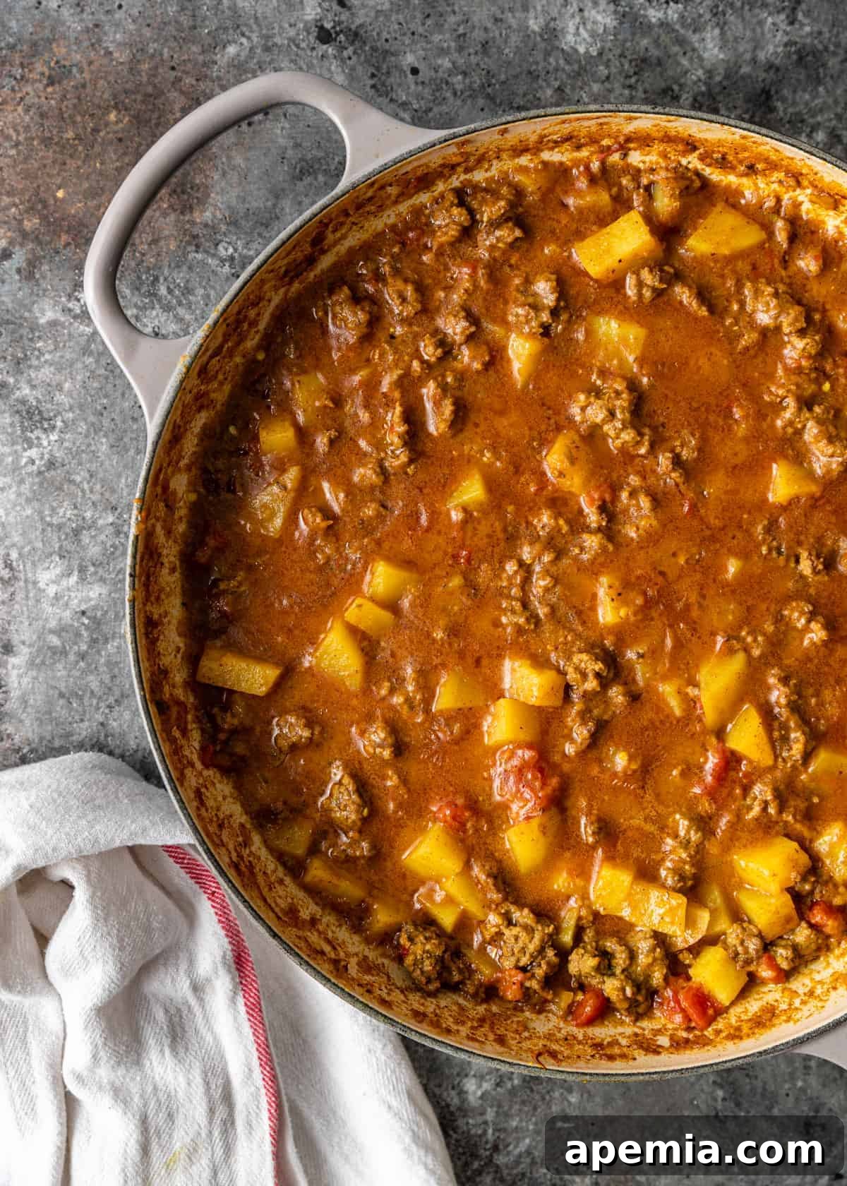 overhead: large pot of keema matar featuring meat and potatoes in tomato and coconut milk sauce
