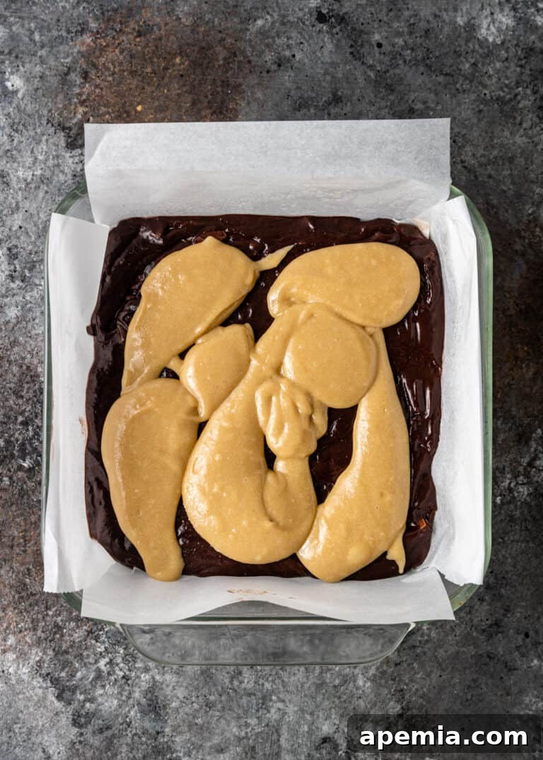 Process shot: Dollops of tahini paste arranged over the chocolate brownie batter, ready for swirling.