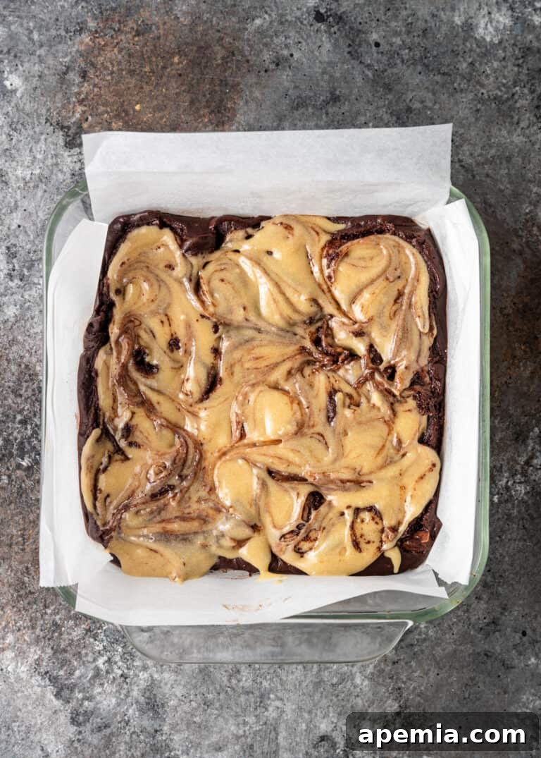 Process shot: Tahini brownie batter with a beautiful swirl pattern in a parchment-lined baking pan before baking.