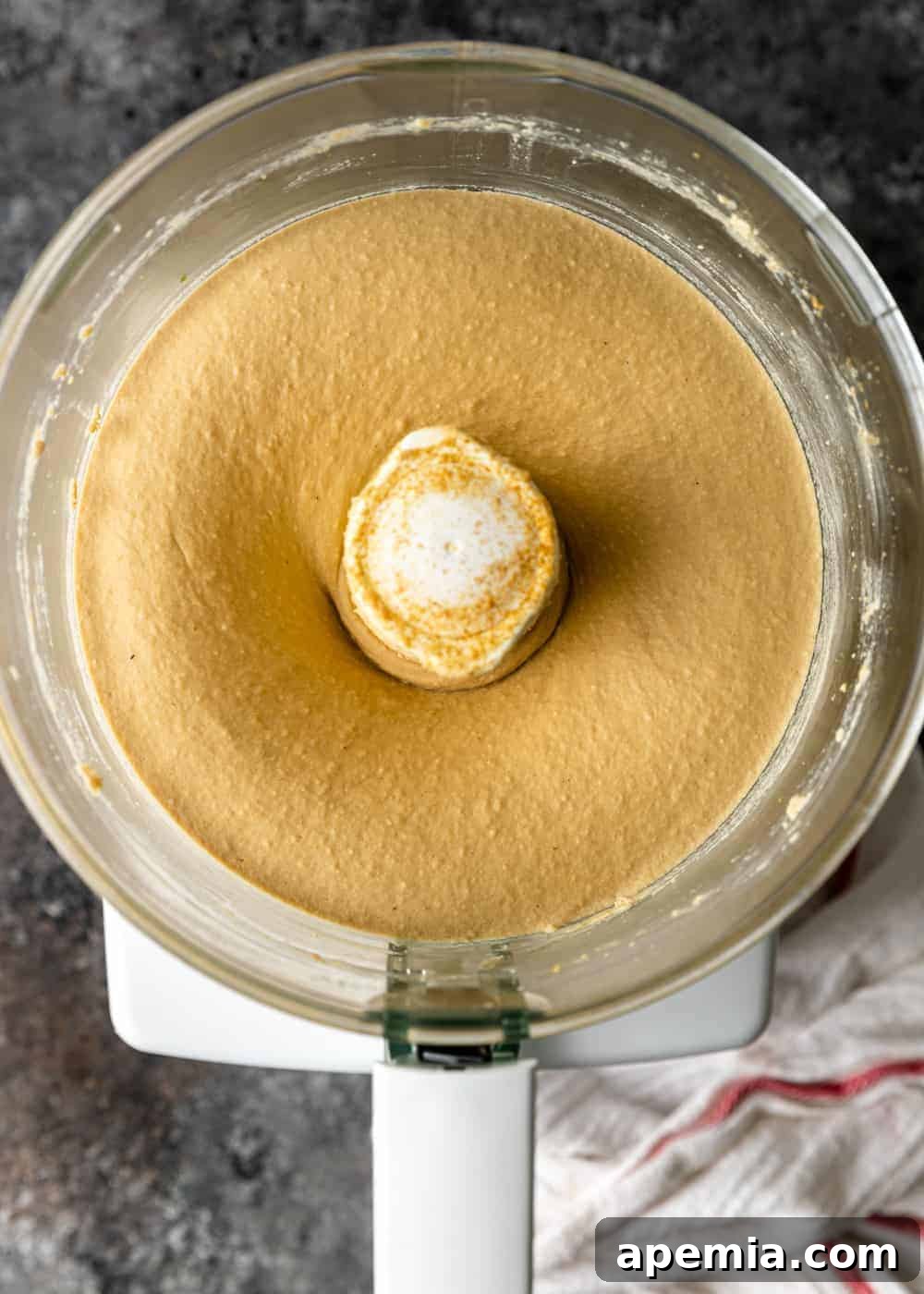An overhead view capturing the process of making hummus inside a food processor bowl, showing the creamy mixture blending.