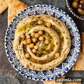 Overhead photo: bowl of homemade Mediterranean hummus garnished with olive oil, spices and whole chickpeas