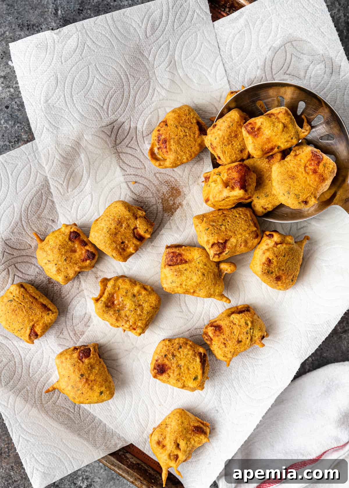 freshly fried cubes of Indian cheese fritters draining on paper towels, golden and perfectly crispy