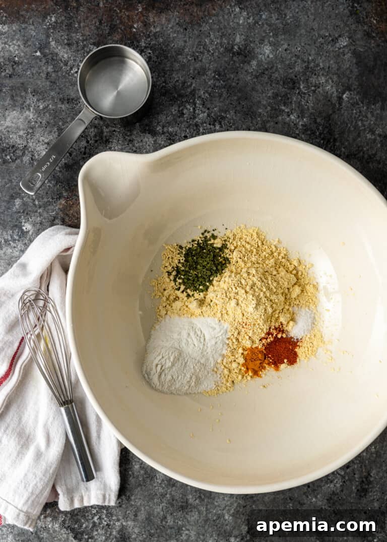 overhead process shot: a bowl containing besan flour and various dry spices, prepped for the batter