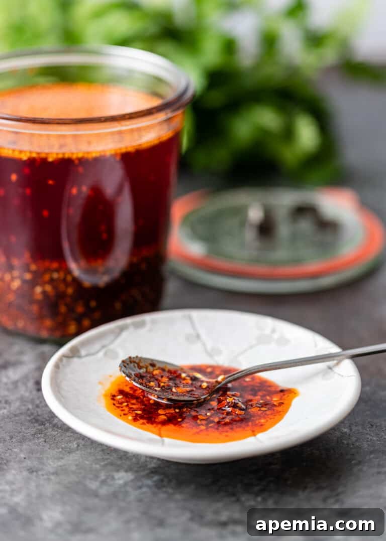 crispy chili oil with spoon on white dish with jar of oil in back