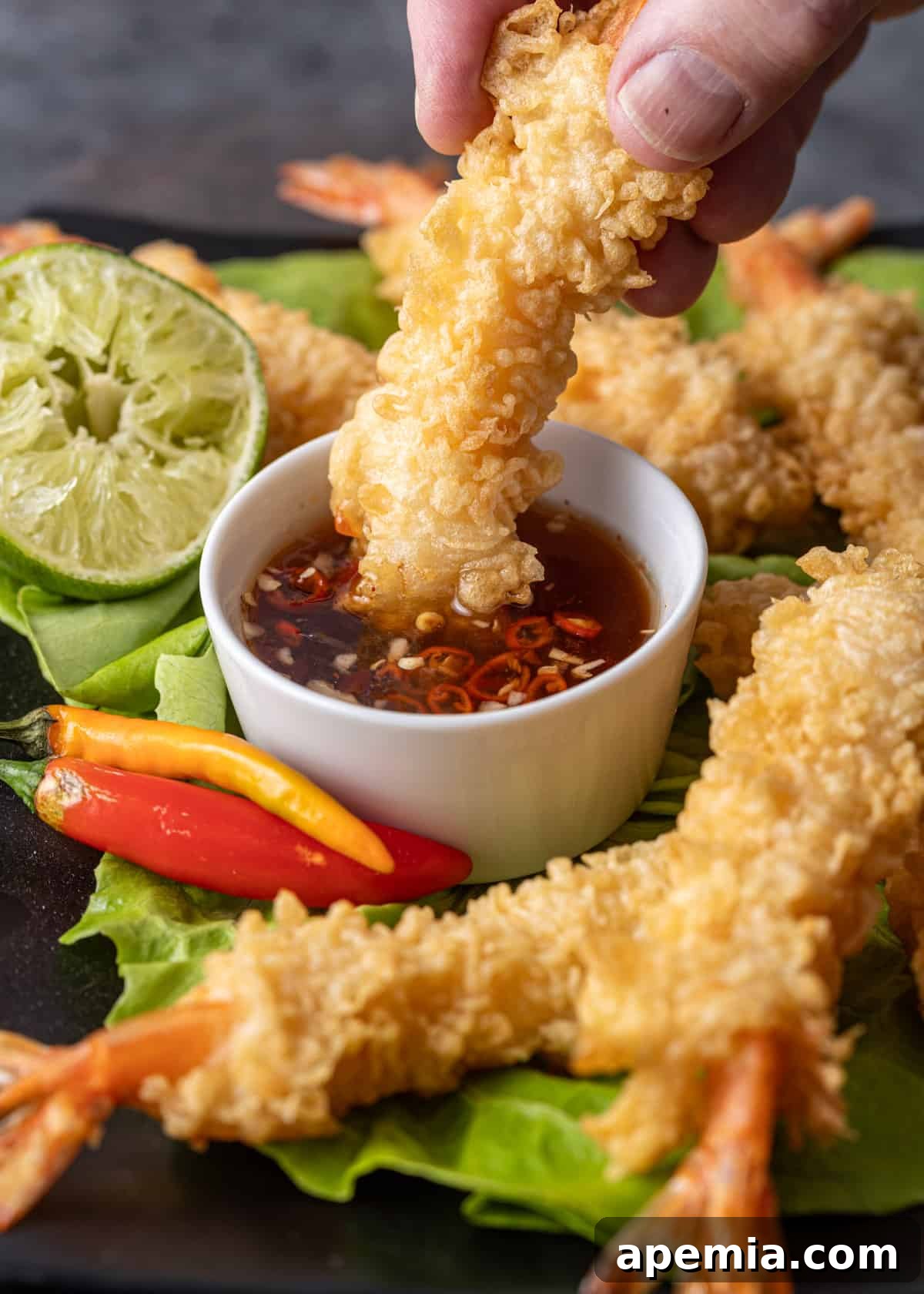 dipping crispy shrimp in a small white bowl of my nuoc cham recipe