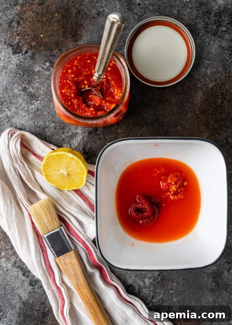 A bowl of vibrant basting sauce made with red bell pepper, red onion, and chili paste, for grilled chicken.