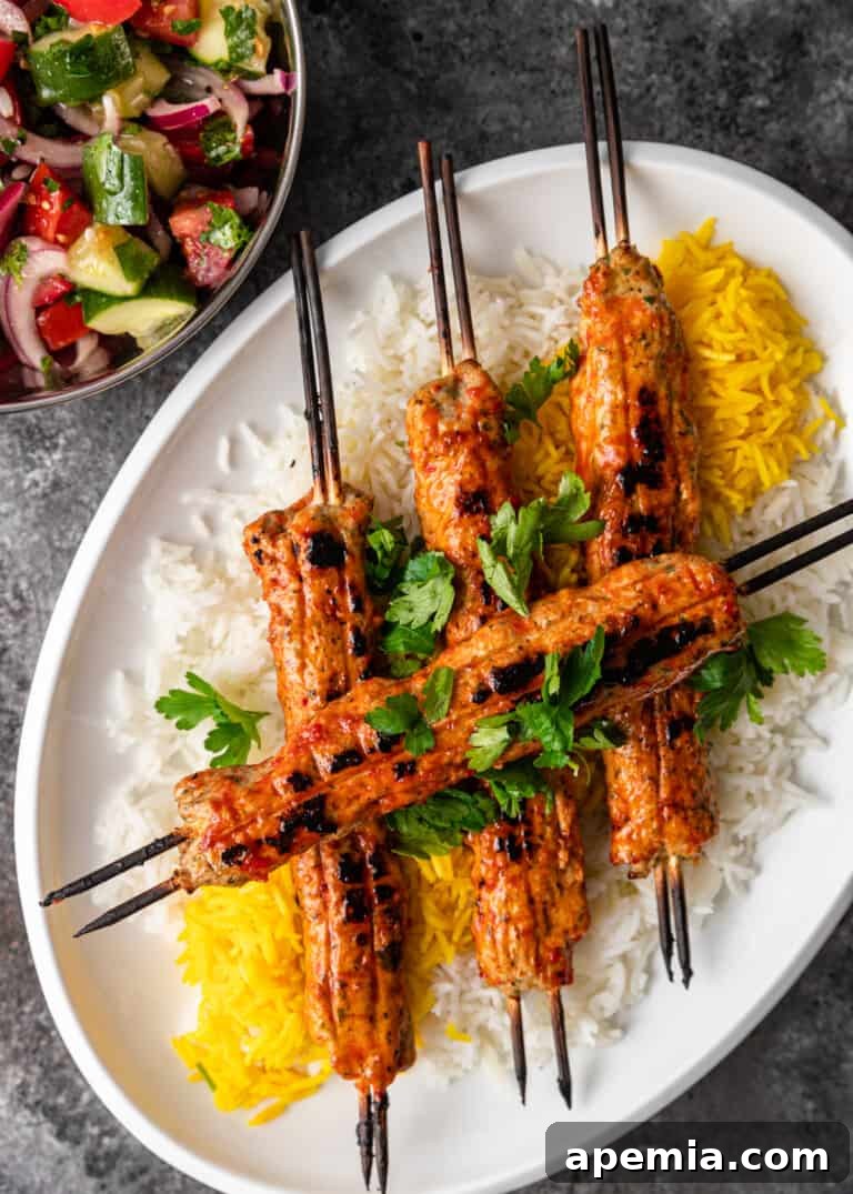 Overhead view of cooked Persian chicken skewers artfully arranged on a platter of fluffy cooked rice.