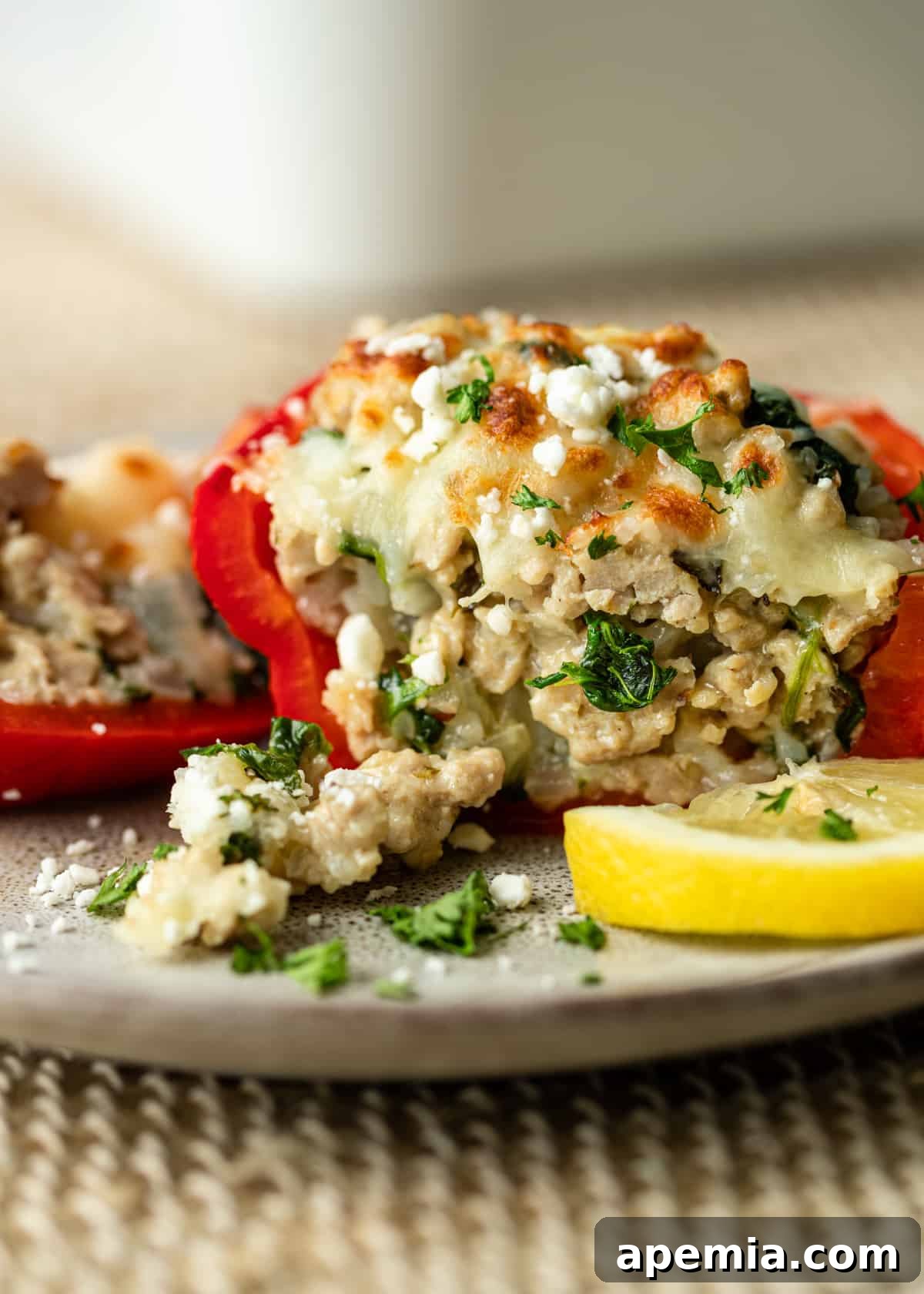 Side view of a Greek stuffed pepper recipe cut in half, revealing the perfectly cooked filling of chicken, spinach, and cheese.