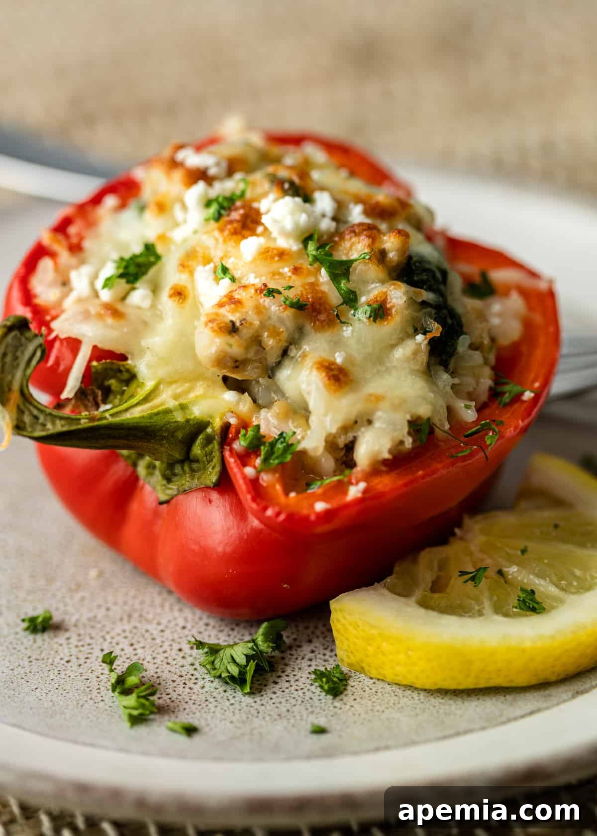 Chicken, spinach, and feta stuffed red pepper, garnished with fresh herbs and a lemon wedge, ready to be served.