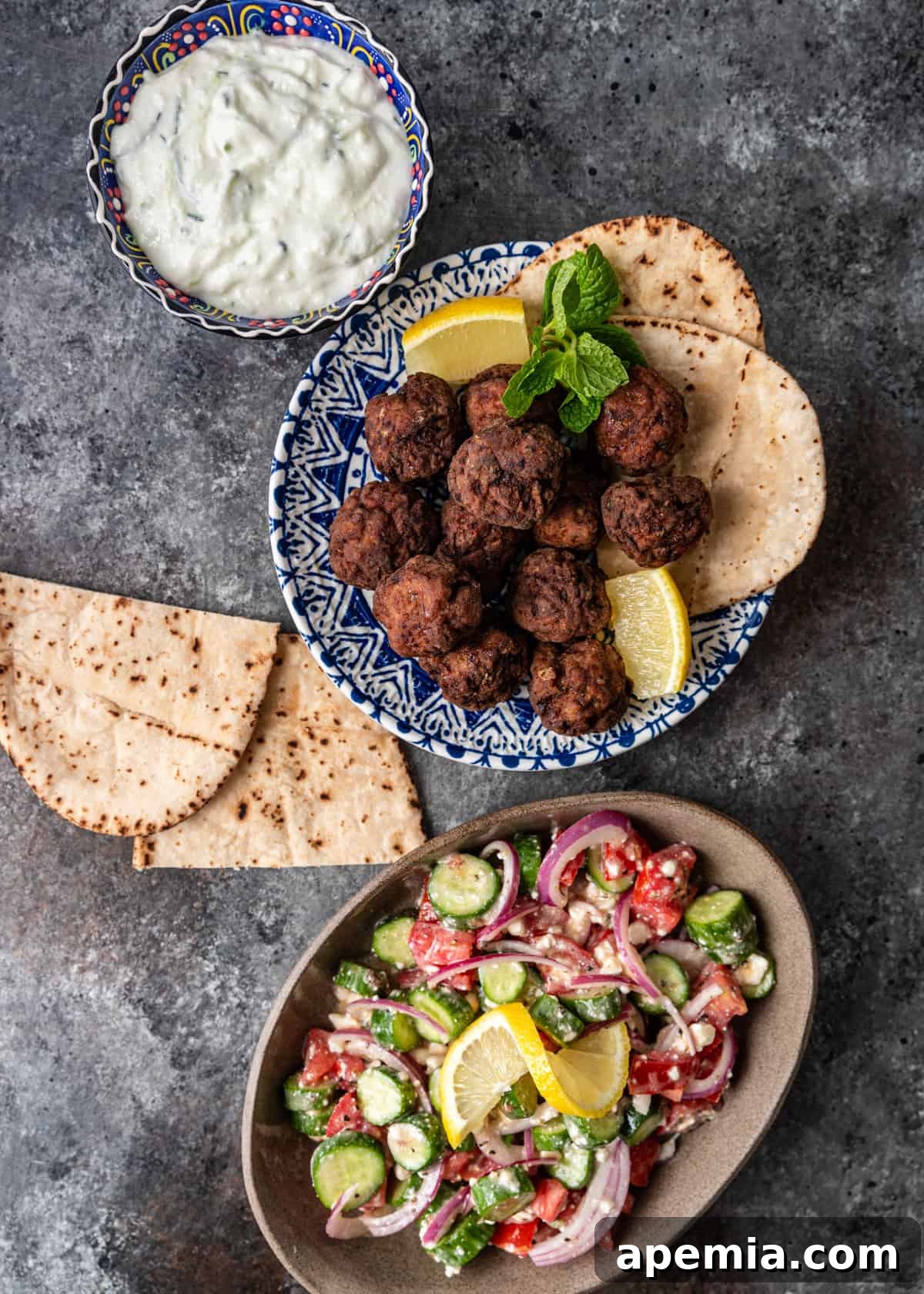 Authentic Pan-Fried Greek Lamb Keftedes 7 overhead: keftedes ready to serve with a variety of dipping sauces on a wooden board