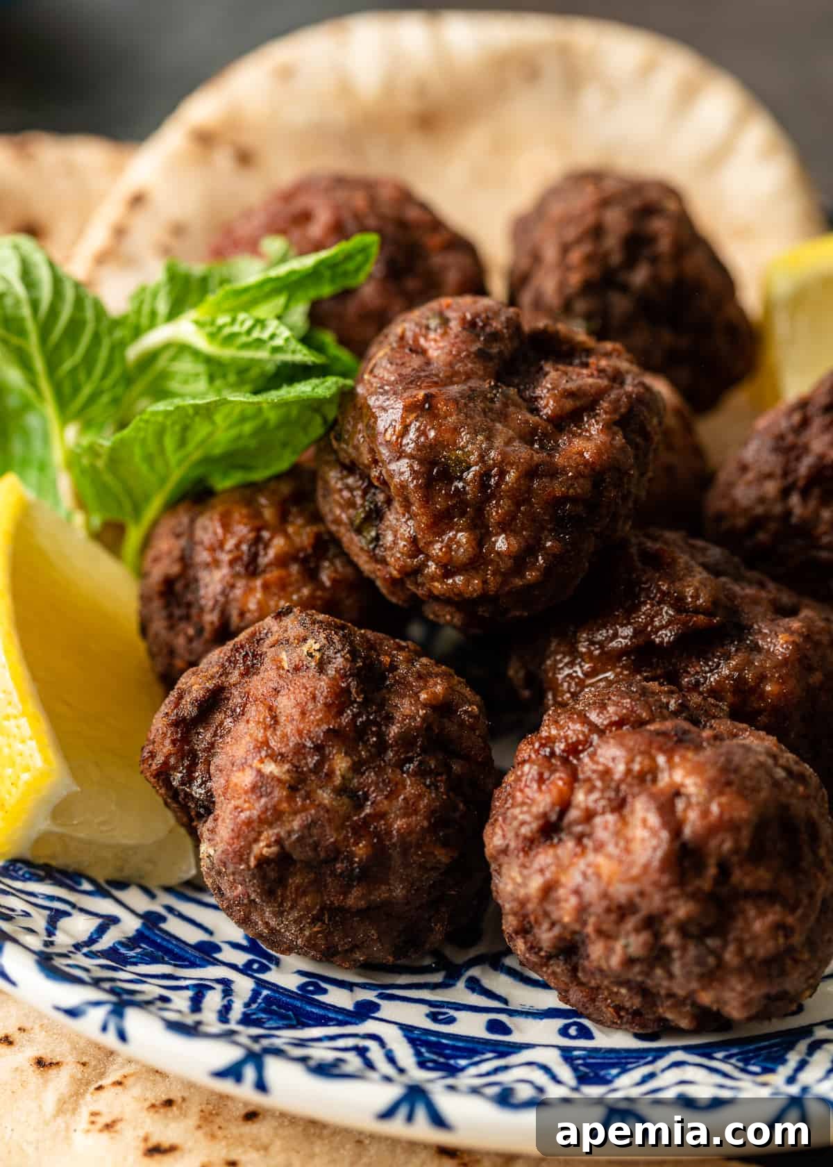 Authentic Pan-Fried Greek Lamb Keftedes 8 closeup: greek lamb meatballs ready to eat, garnished with fresh herbs and a lemon slice