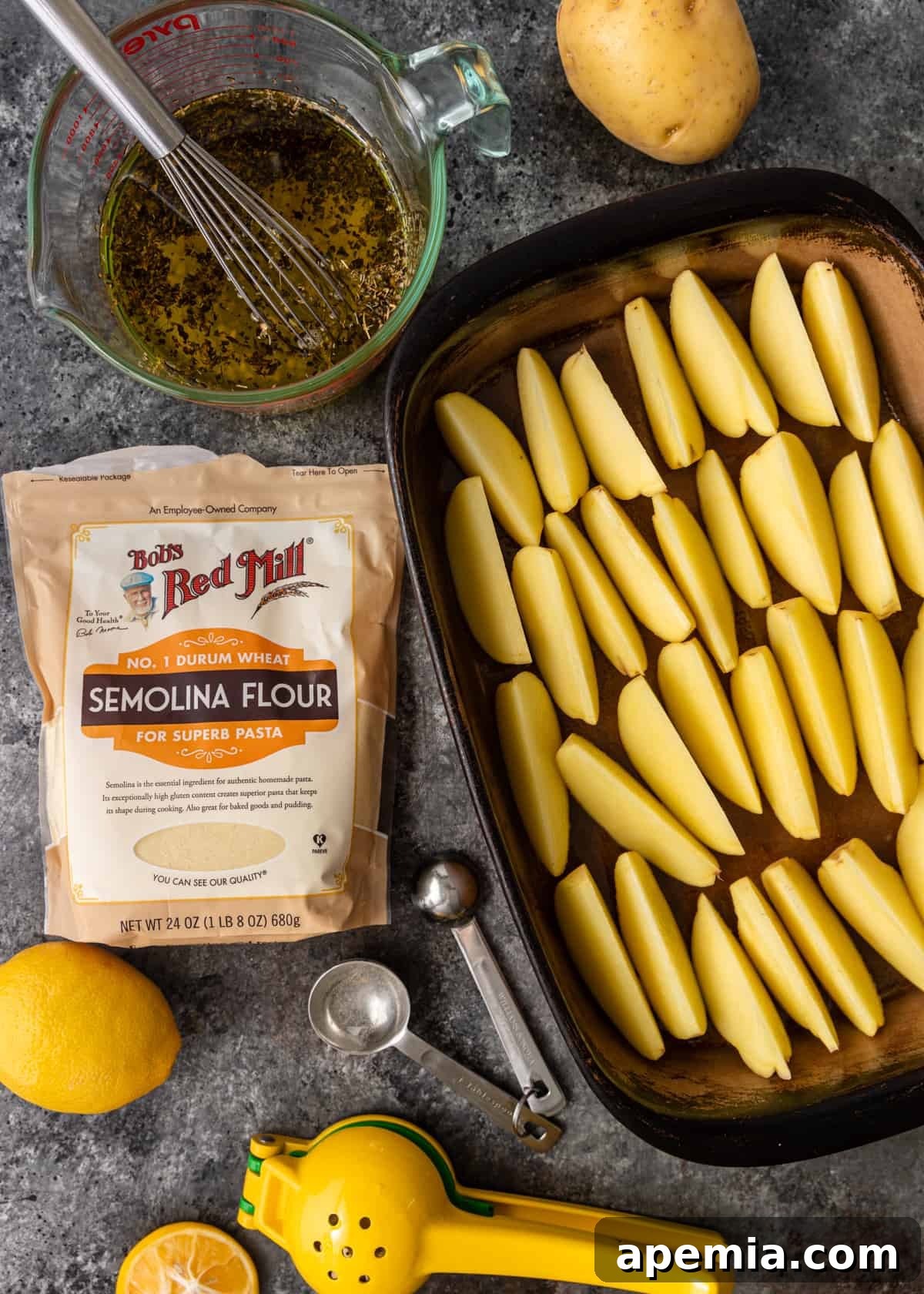 overhead: potato wedges in baking pan next to ingredients for roasting, including lemon and oregano