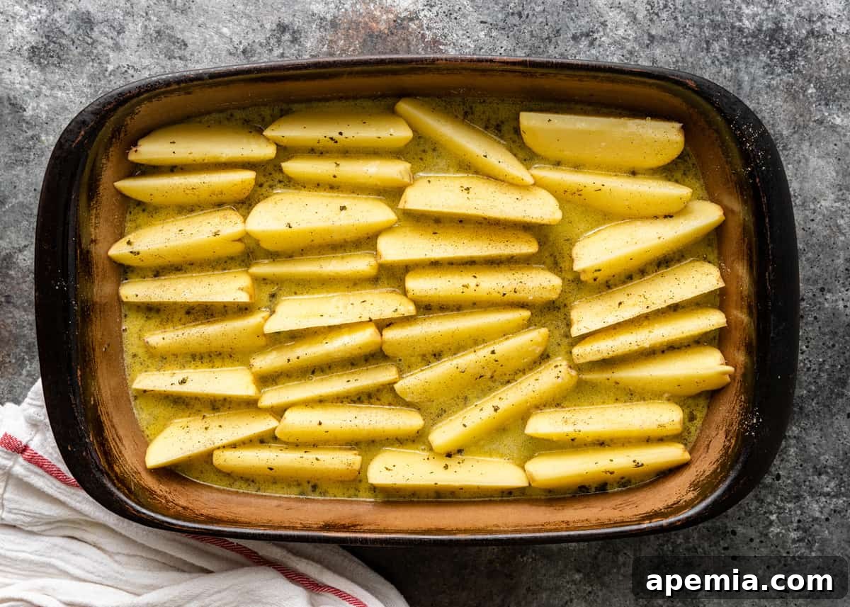 overhead: marinated potato wedges in baking pan, ready for roasting