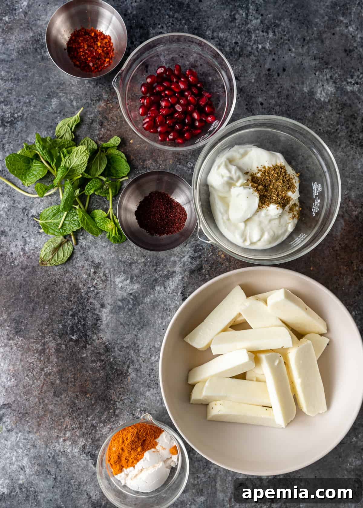 Overhead shot of all the fresh ingredients laid out for the halloumi fries recipe, including a block of halloumi, spices, and topping components.