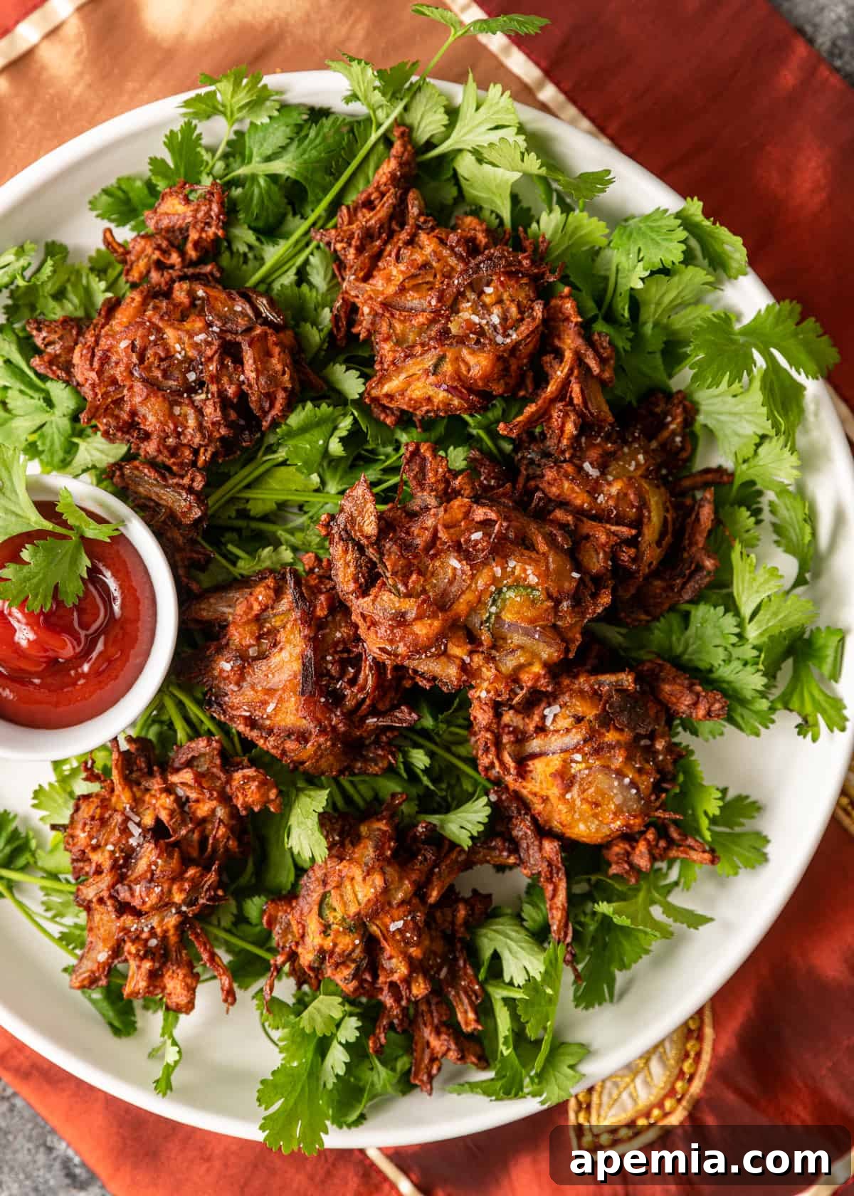 Overhead shot of Onion Pakoras on a plate with dipping sauce, ready to be served