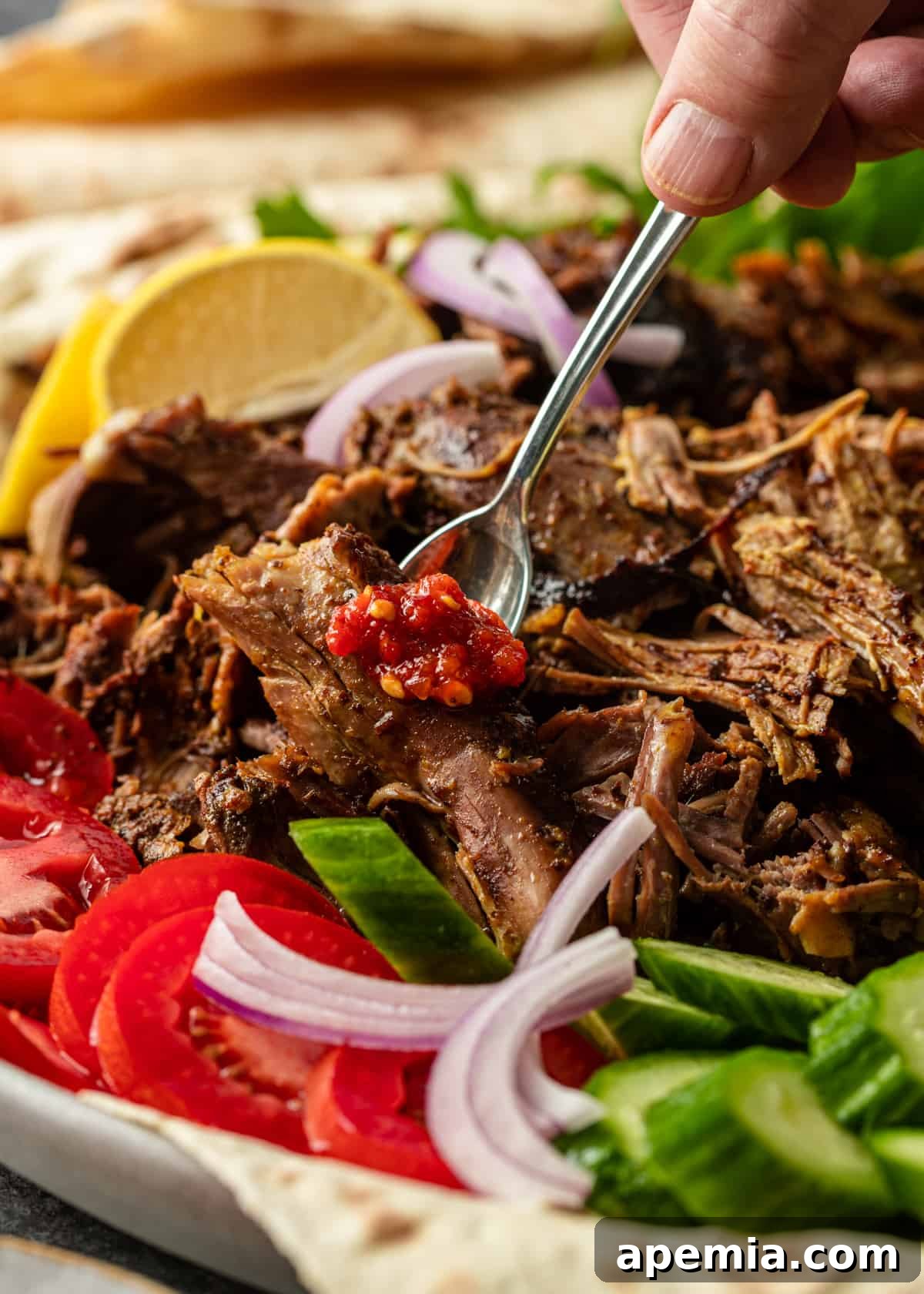 Close-up action shot of shredded lamb shawarma being scooped from a pan, highlighting its tender texture and rich juices, ready for serving.