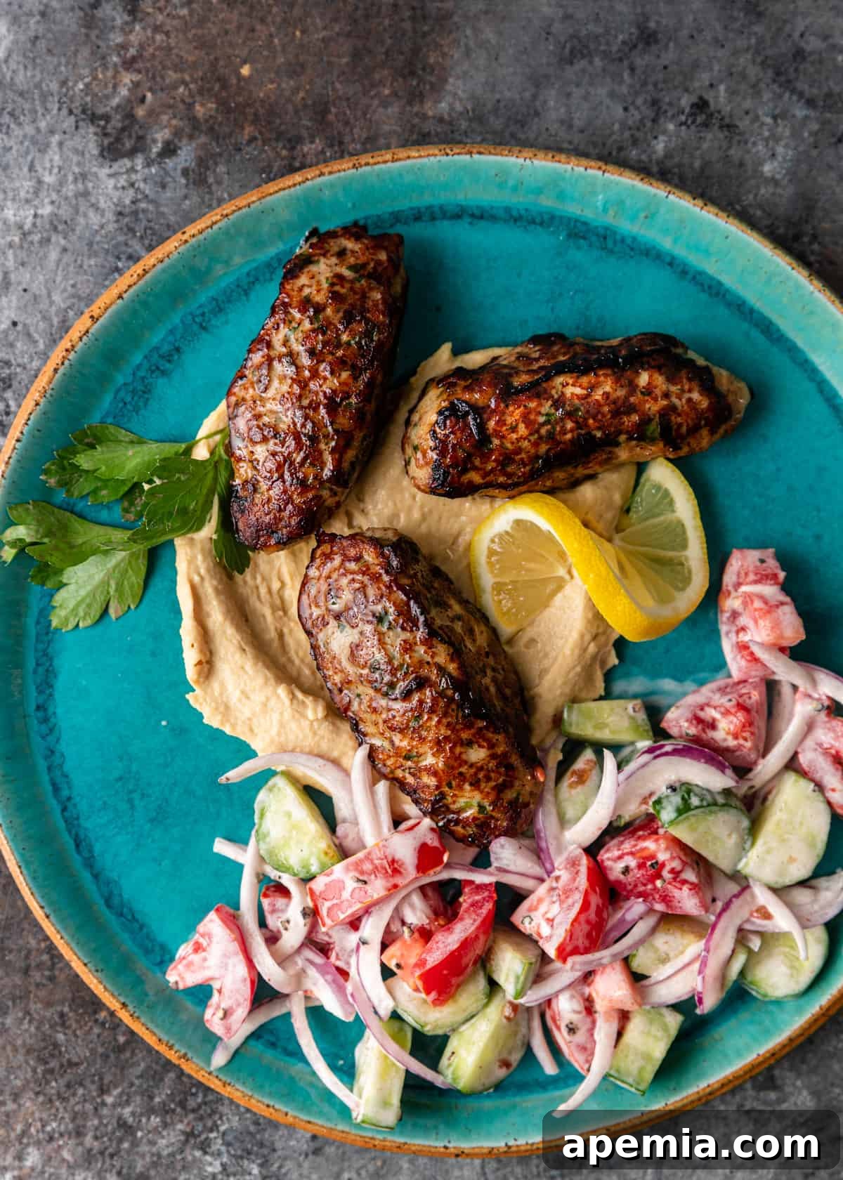 overhead: 3 chicken kofta on a plate of hummus and salad
