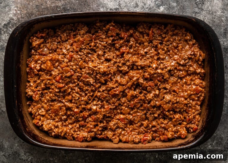 A rich layer of savory meat sauce spread evenly over eggplant in a moussaka dish.