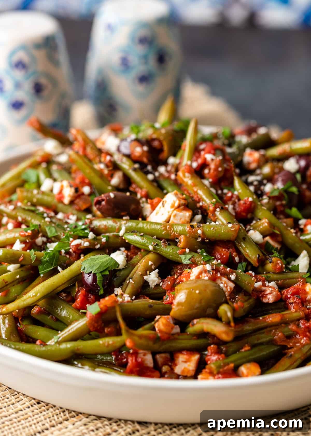 closeup: my fasolakia recipe in a white bowl with olives and feta on top