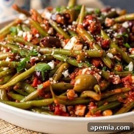 close up of Fasolakia - Greek Green Beans in a white serving bowl.