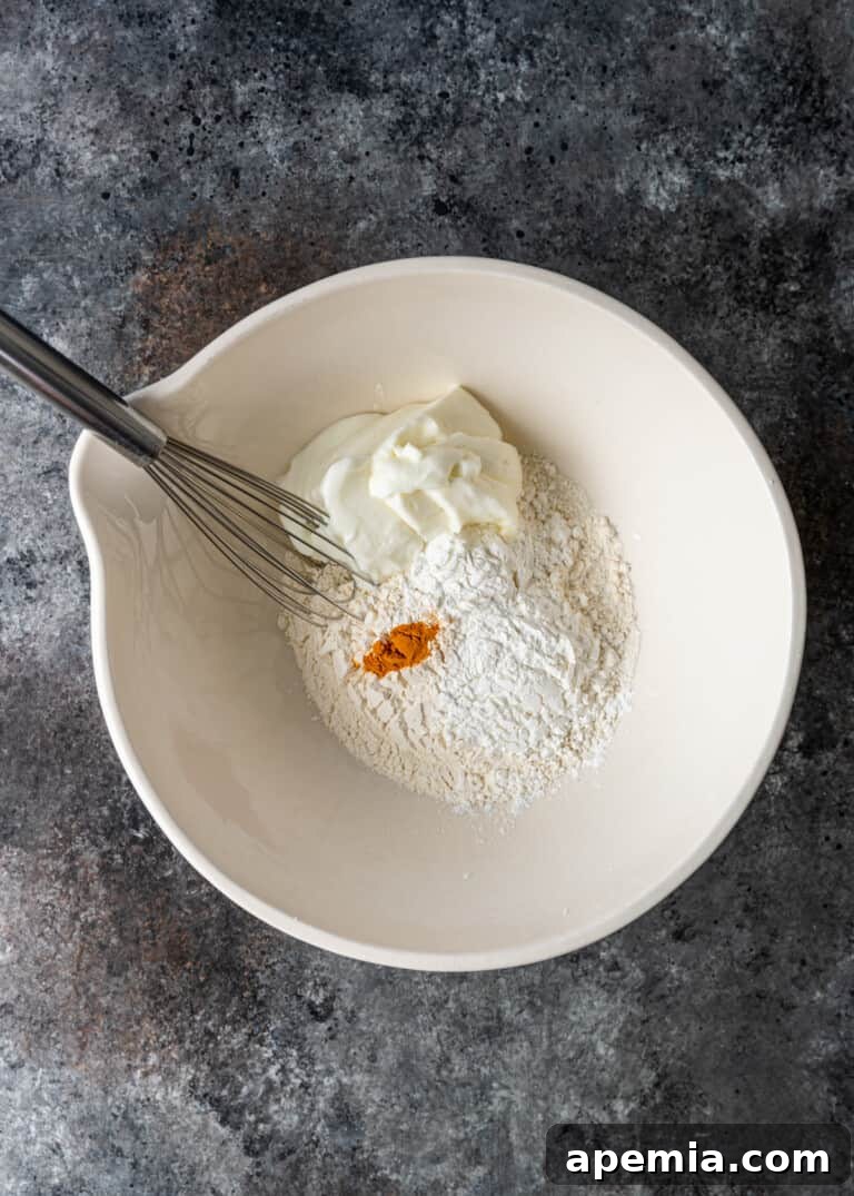 overhead shot of combining dry and wet ingredients in a bowl for jalebi batter