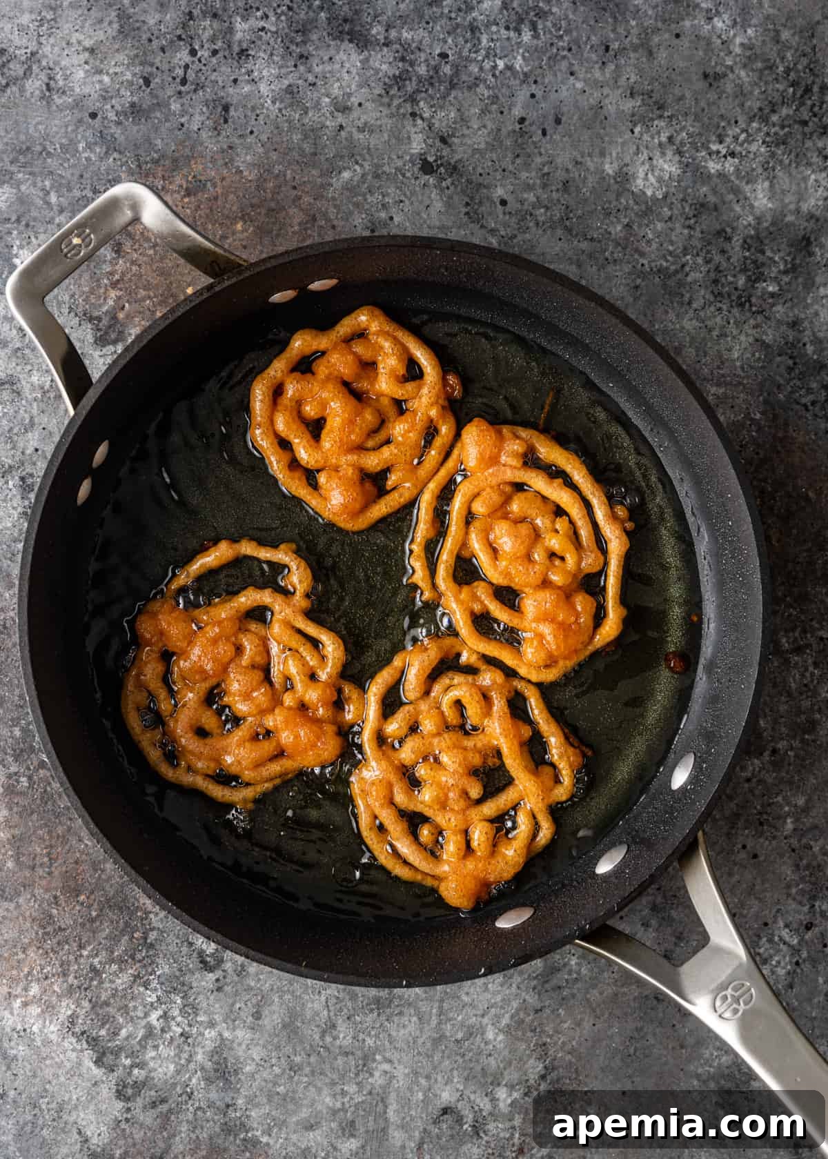 overhead shot of frying Indian funnel cake batter in a pan, forming intricate spirals
