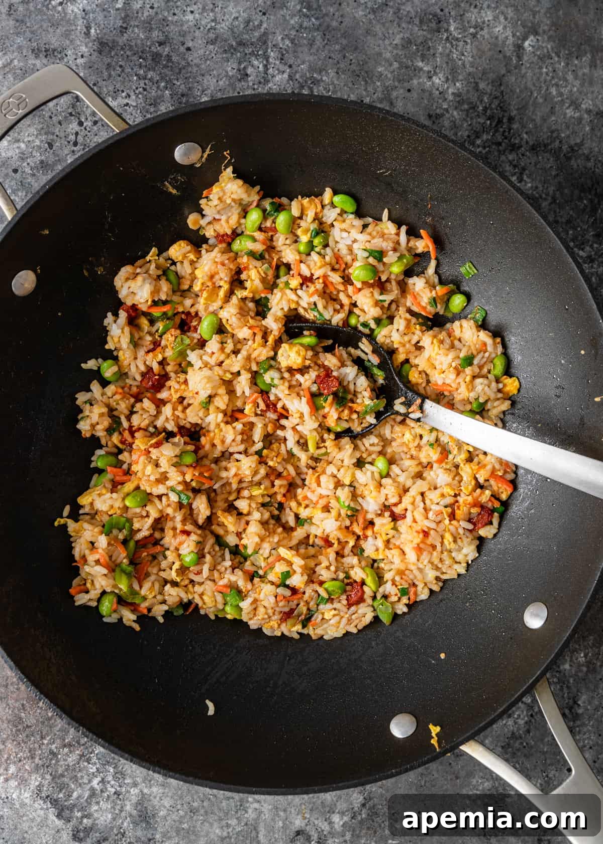 overhead shot: a wok filled with sizzling hibachi fried rice, actively being stirred
