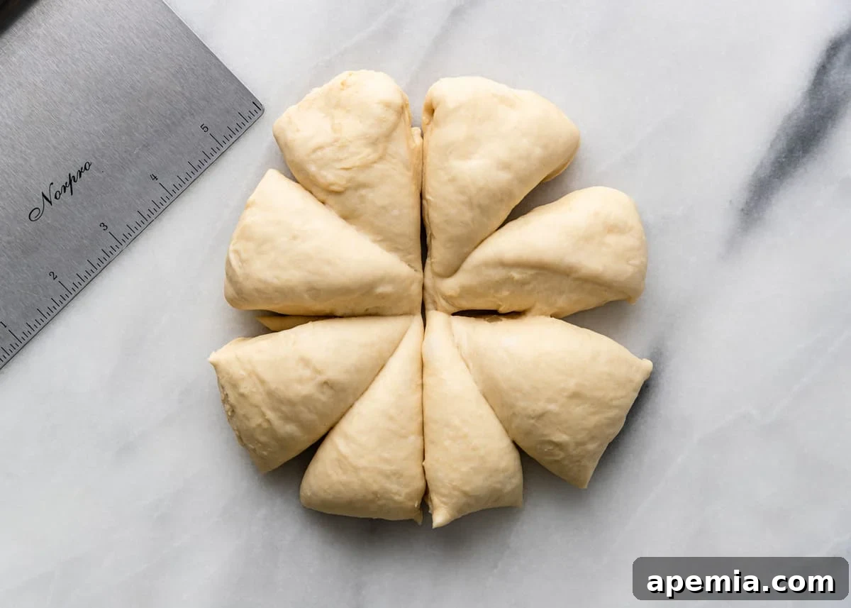 Overhead shot of a large naan dough ball, freshly cut into equal portions on a marble countertop.