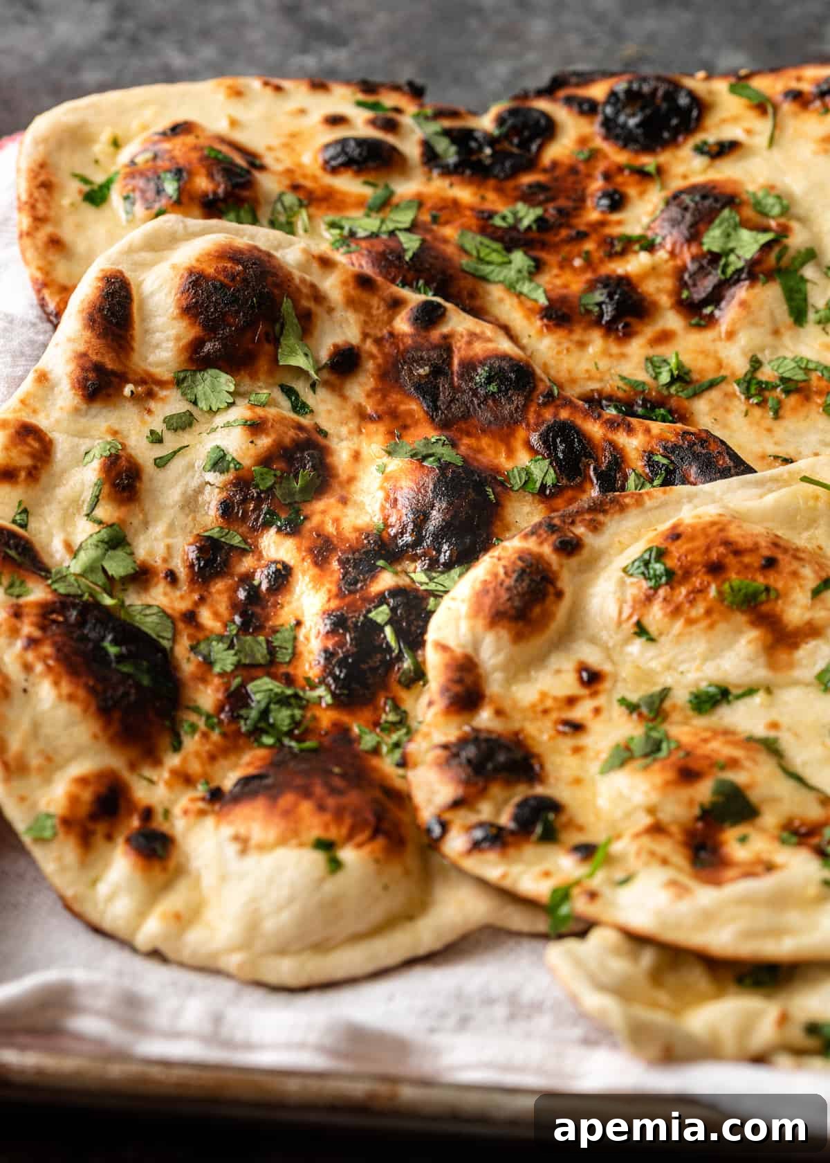 Close-up shot of buttered naan bread with fresh cilantro, showcasing its soft texture and glistening surface.