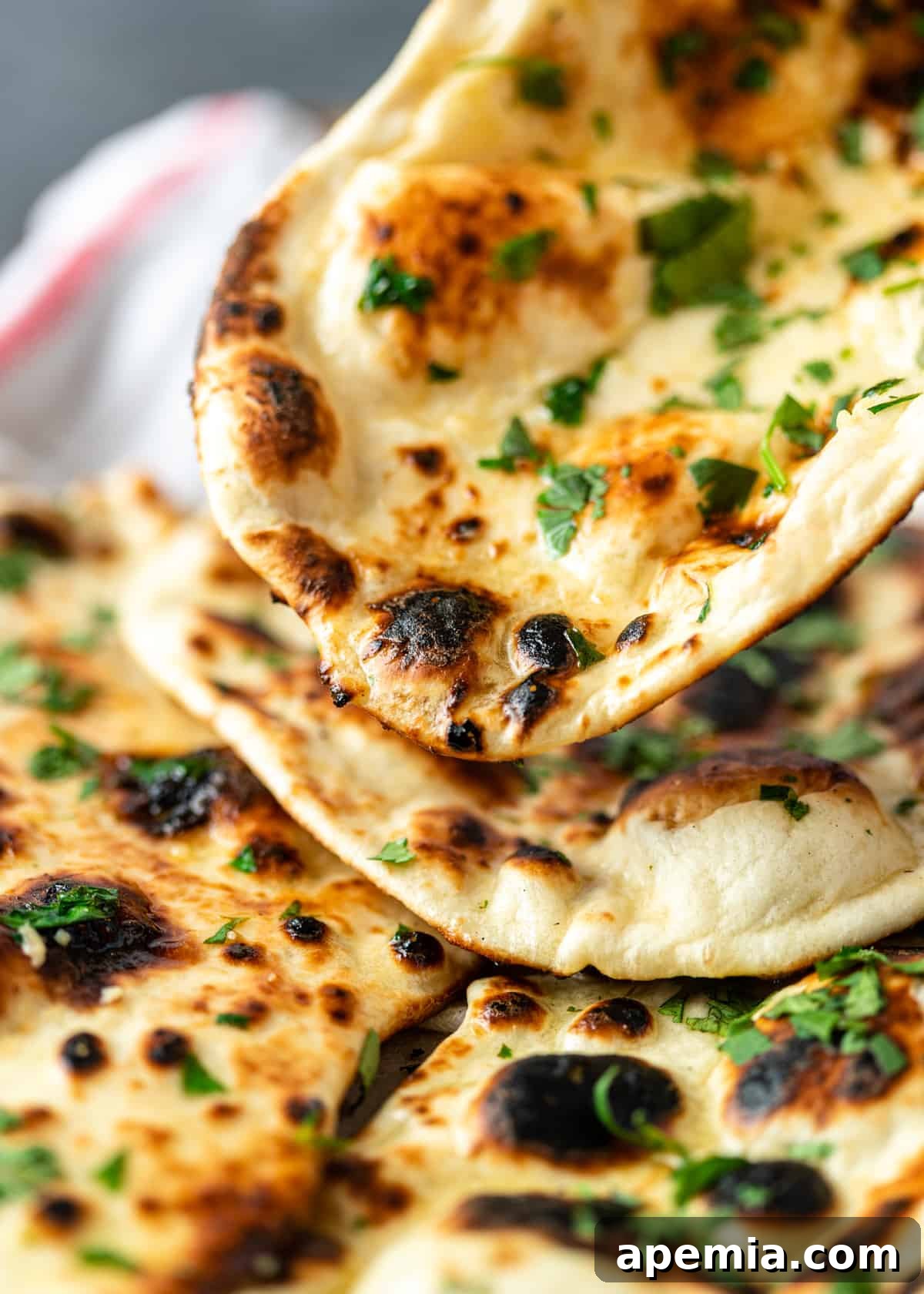 Close-up shot of a stack of fluffy naan bread with cilantro, ready to be served.