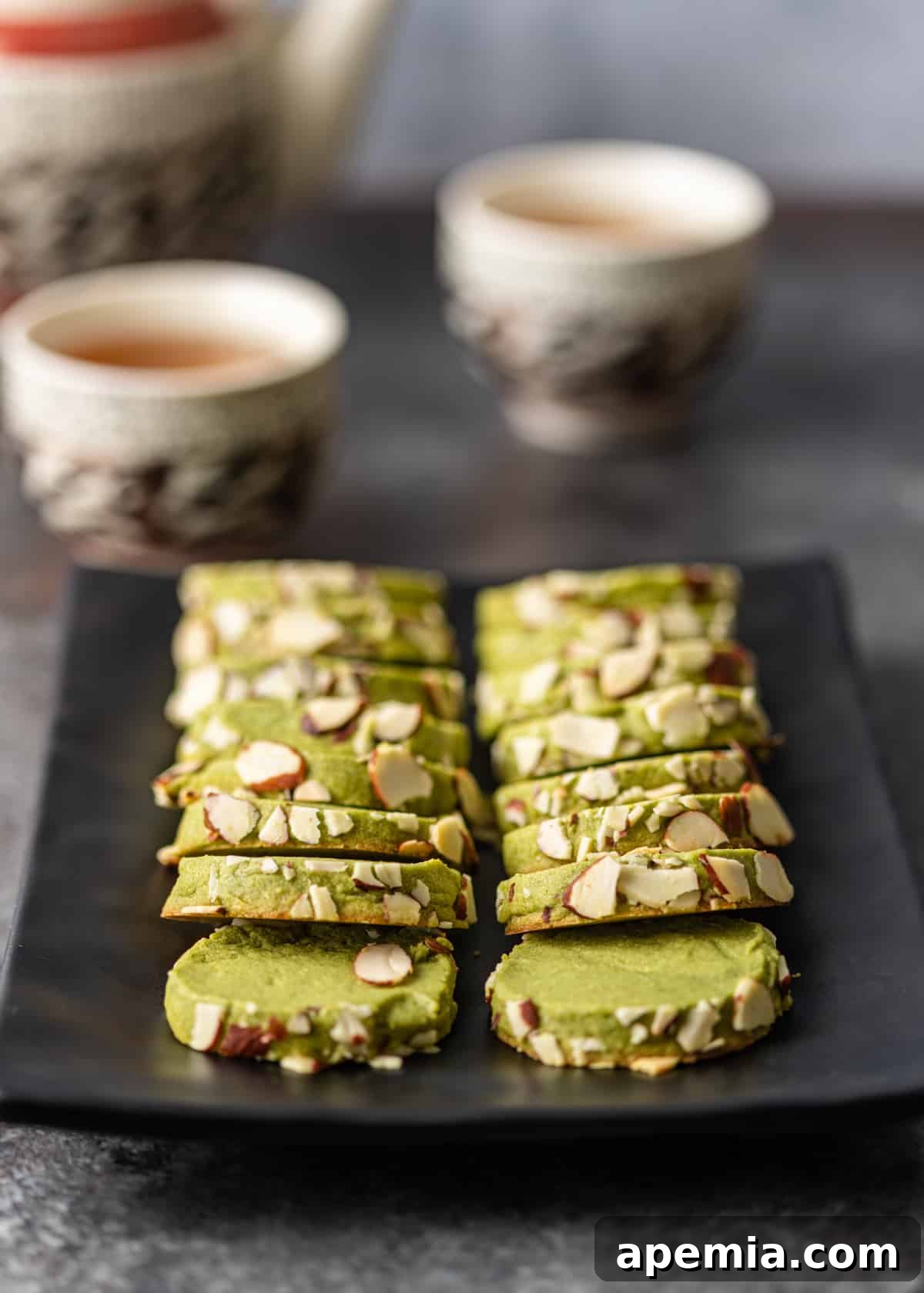 Closeup overhead view of several vibrant green matcha cookies beautifully arranged on a black platter, ready to be served.