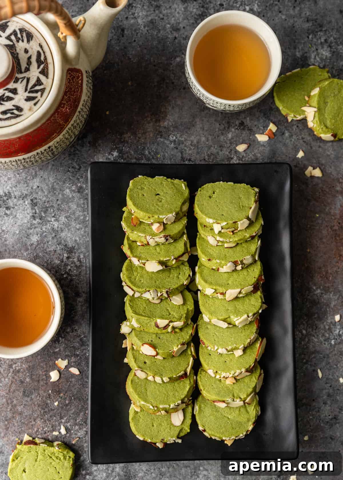 Overhead view of several green tea shortbread cookies arranged on an elegant black platter.
