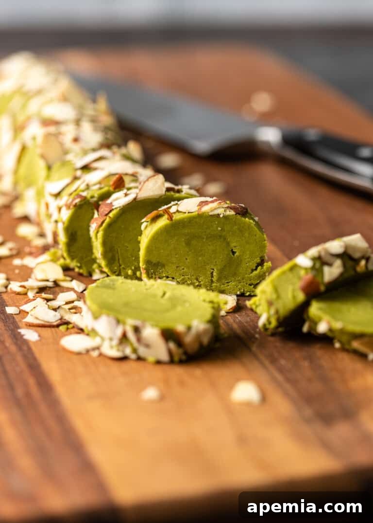 Side view process shot: neatly sliced matcha cookies arranged on a cutting board, with a sharp knife resting beside them.