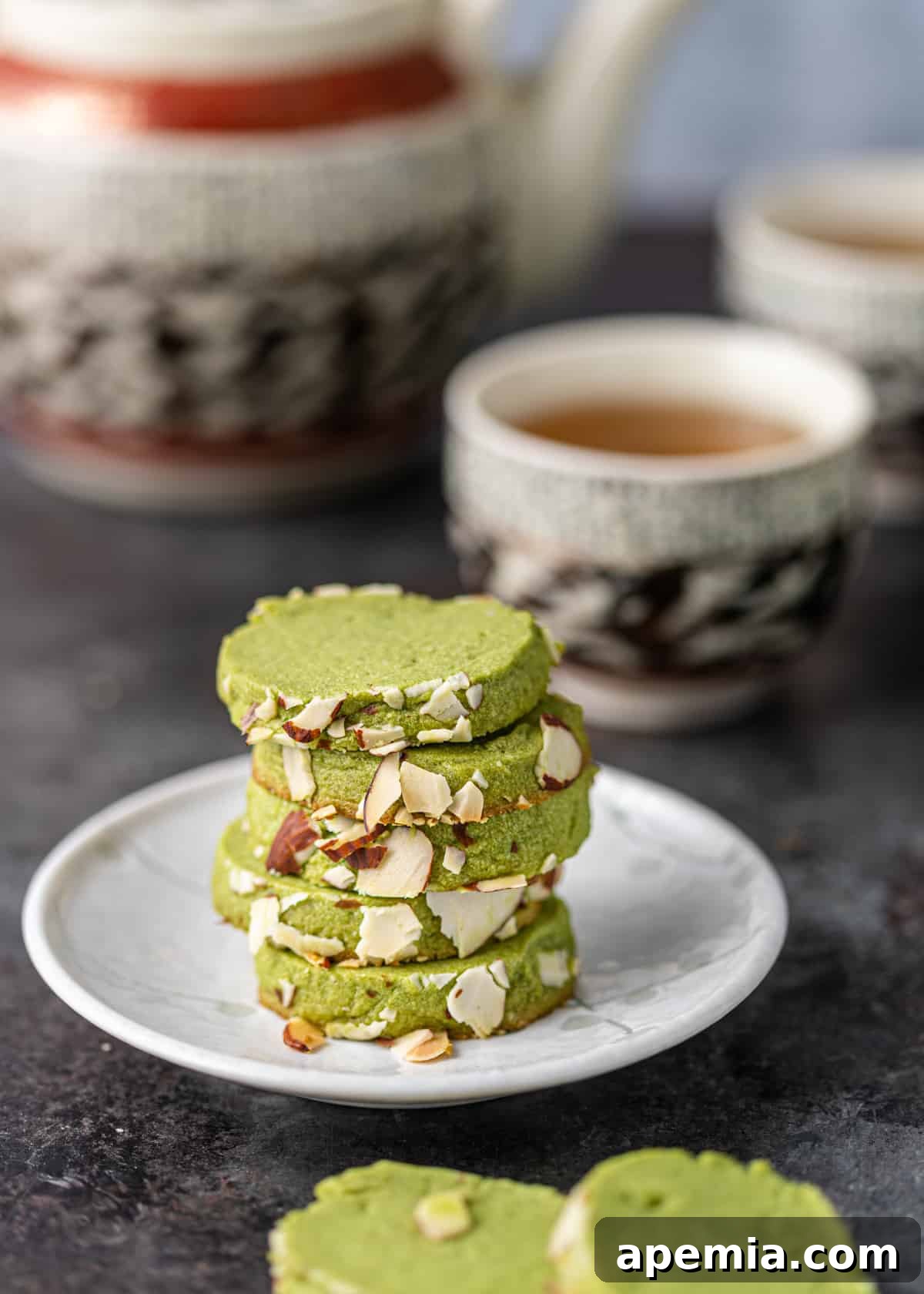 Closeup side view of a stack of vibrant green matcha cookie recipe on a white plate, ready to be enjoyed.