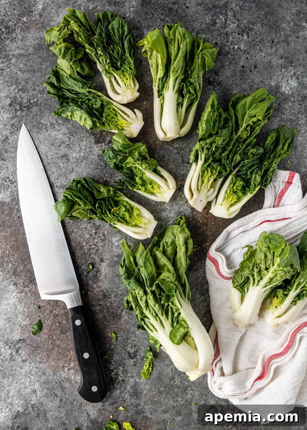 several heads of baby bok choy next to chef's knife