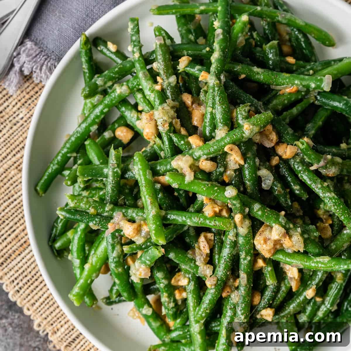 Sesame Garlic Green Beans 2 overhead: vibrant Asian green beans topped with crunchy peanuts on a white plate