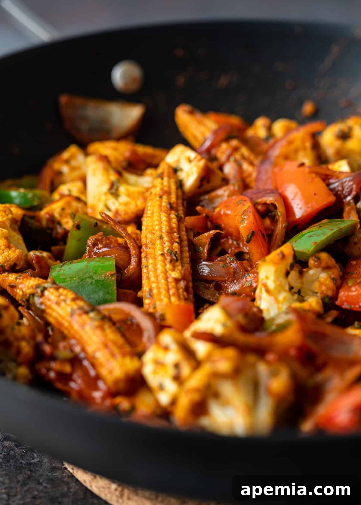 closeup: baby corn and cut bell peppers for jalfrezi in wok