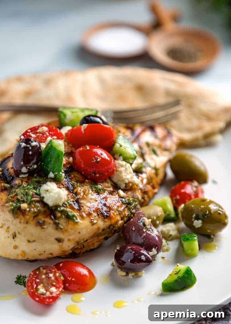 Mediterranean Grilled Chicken served on a plate with fresh tomatoes and olives as garnish.