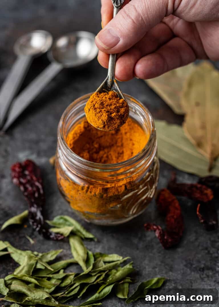 A spoonful of vibrant red Madras Curry Powder, showcasing its fine texture and rich color.
