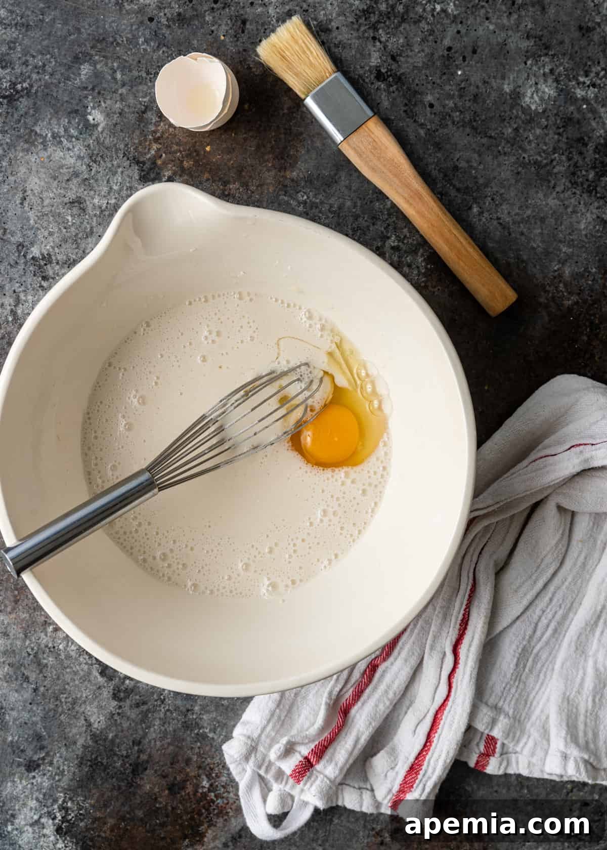 Beloved Turkish Ramadan Pide 17 A bowl containing the prepared egg wash ingredients: a whisked egg, Greek yogurt, and flour slurry, ready for application.