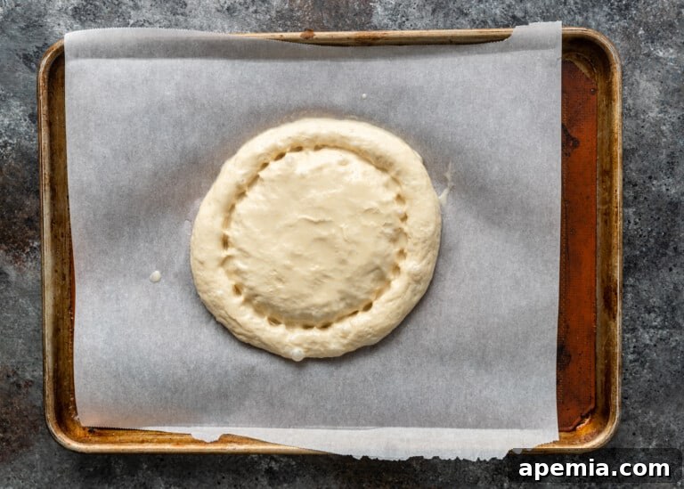Beloved Turkish Ramadan Pide 18 A hand using wet fingertips to make deep circular indentations around the edge of the Ramazan Pidesi dough, after applying the egg wash.