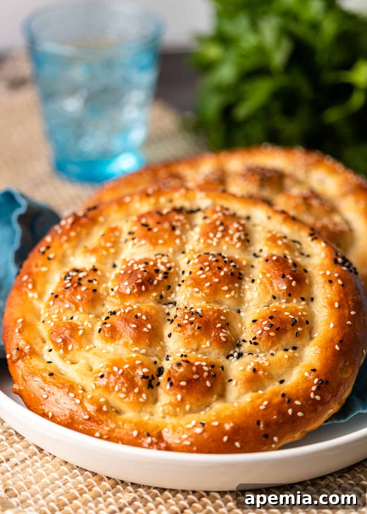 Beloved Turkish Ramadan Pide 22 Two pieces of golden Ramazan Pidesi, freshly baked and ready to be enjoyed, presented on a white plate.
