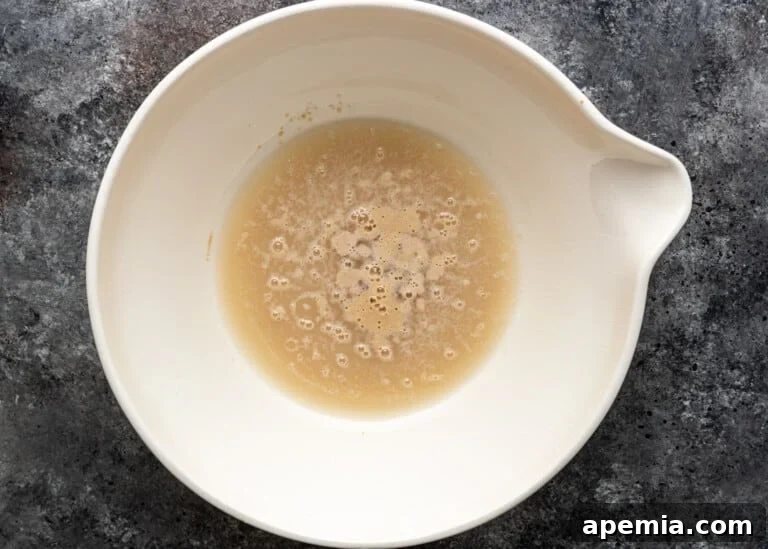 Beloved Turkish Ramadan Pide 5 Warm water and sugar mixed with yeast in a bowl, showing the yeast starting to activate.