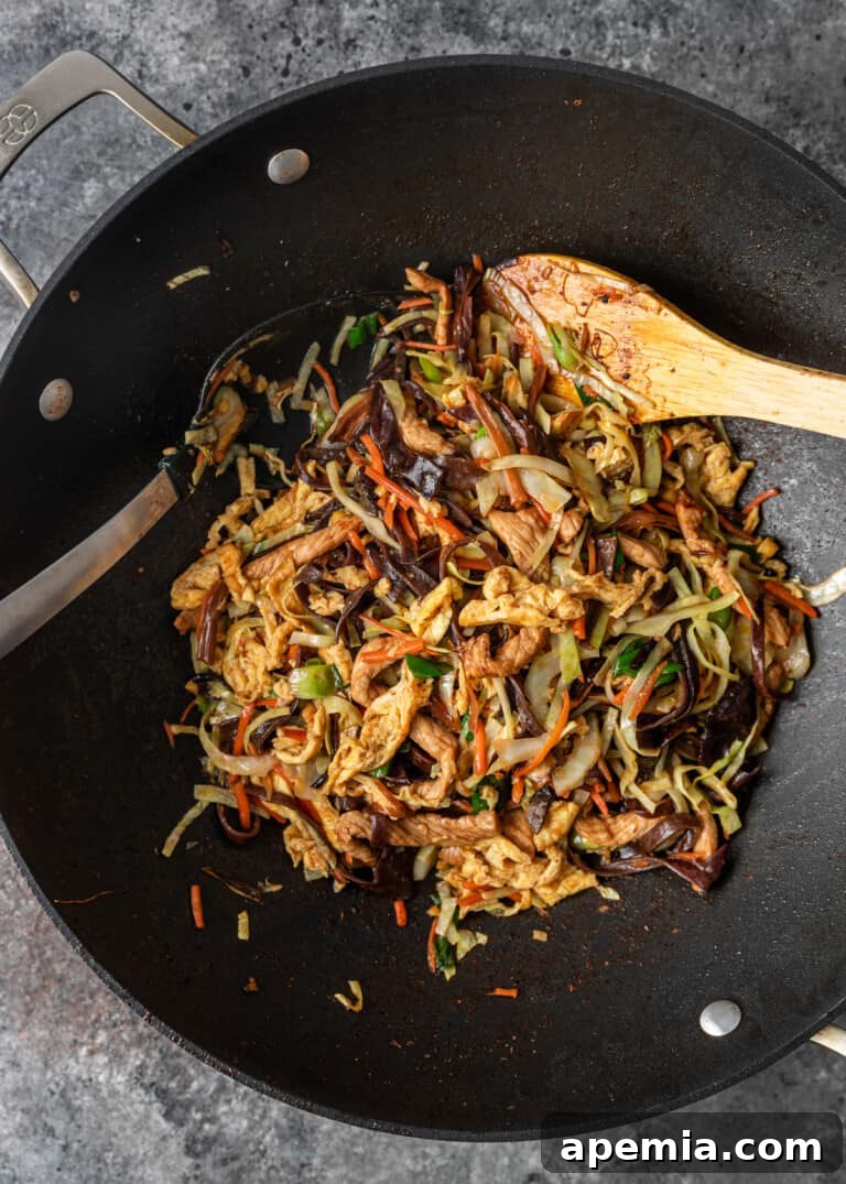 pork and egg added back into stir-fried vegetables in a wok