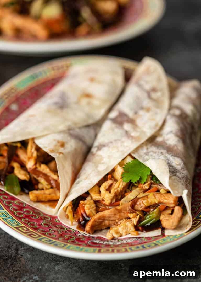 a wrapped Moo Shu Pork pancake on a plate, ready to be eaten