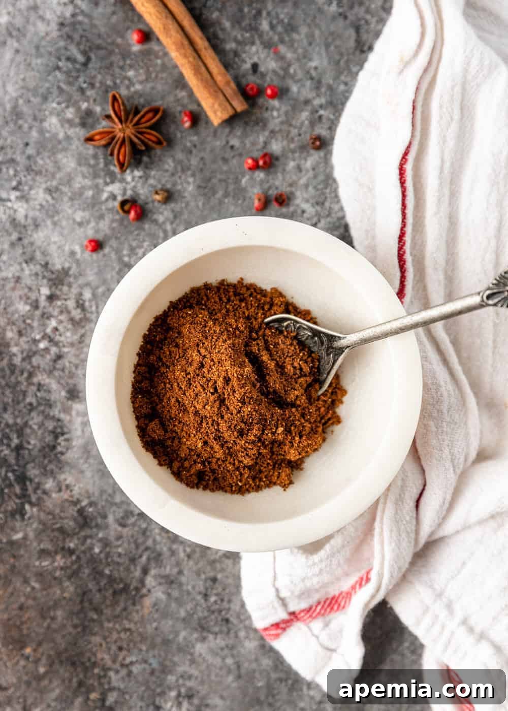 overhead: small white bowl on a counter with five spice powder and a small metal spoon