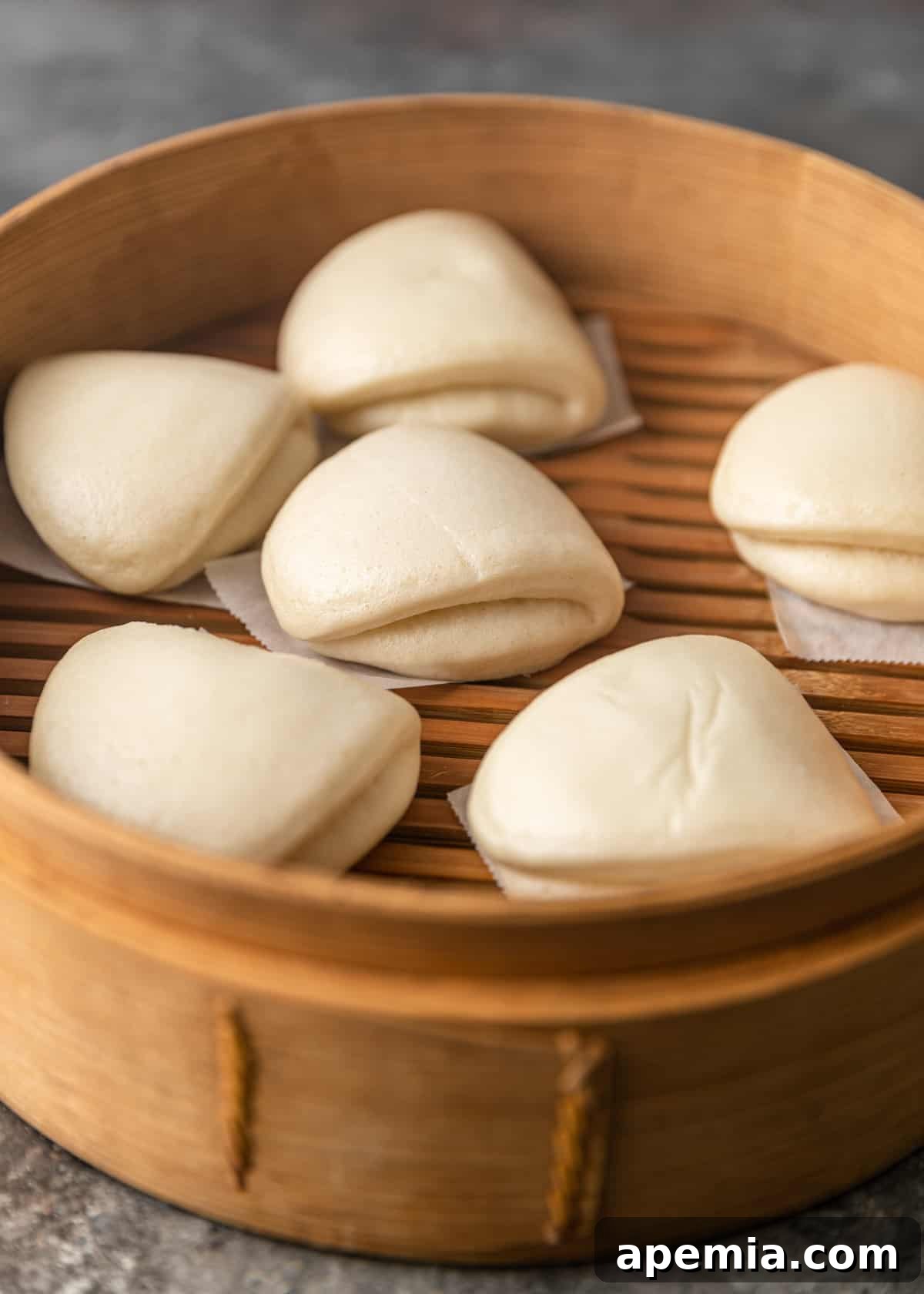 closeup: bao buns in a wooden steamer ready to be filled with pork belly