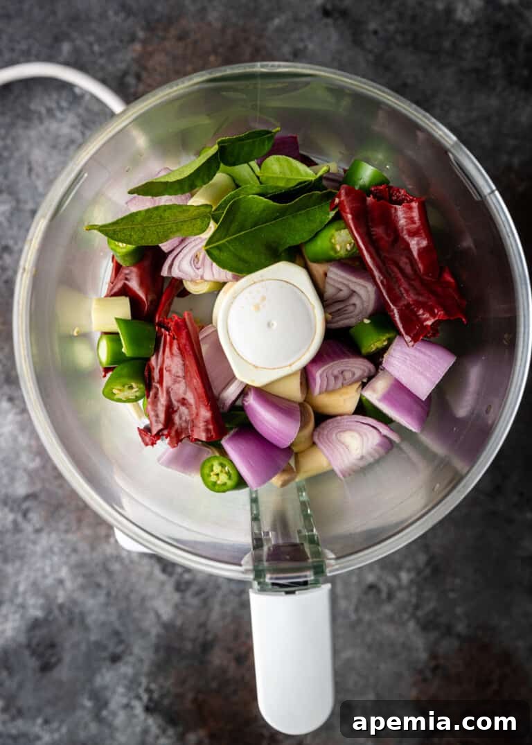 overhead process shot: fresh ingredients including chilis, garlic, and aromatics for panang curry paste