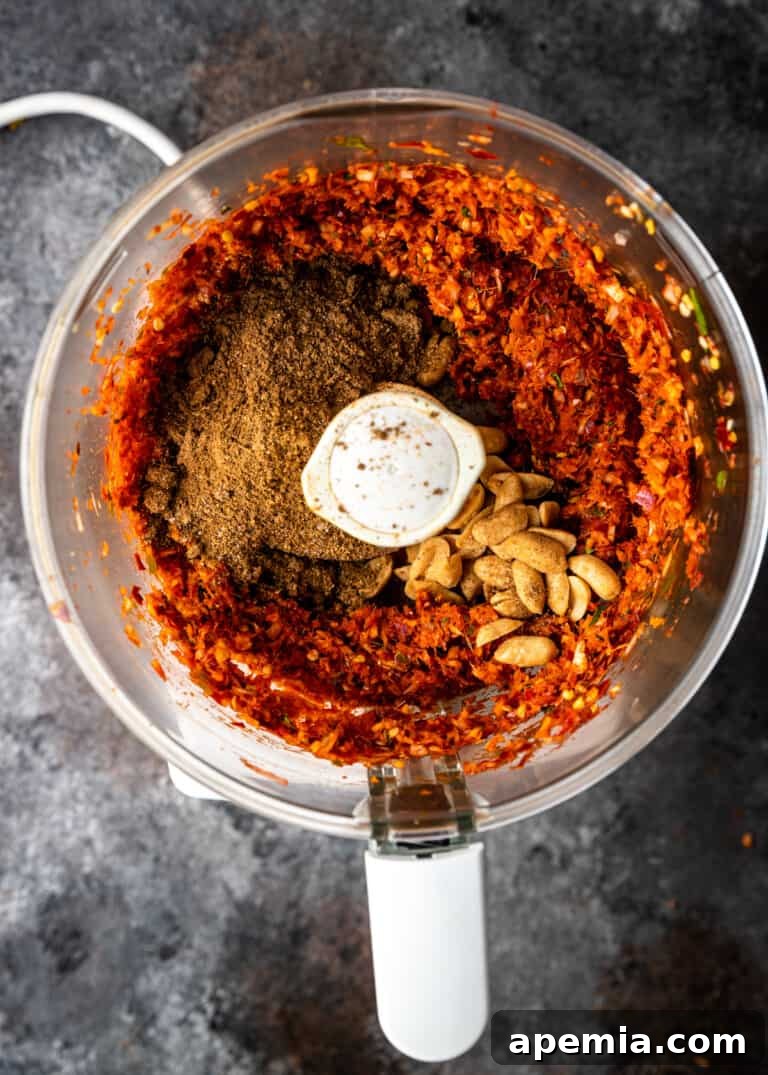 overhead process shot: adding ground spices and roasted peanuts to the curry paste mixture